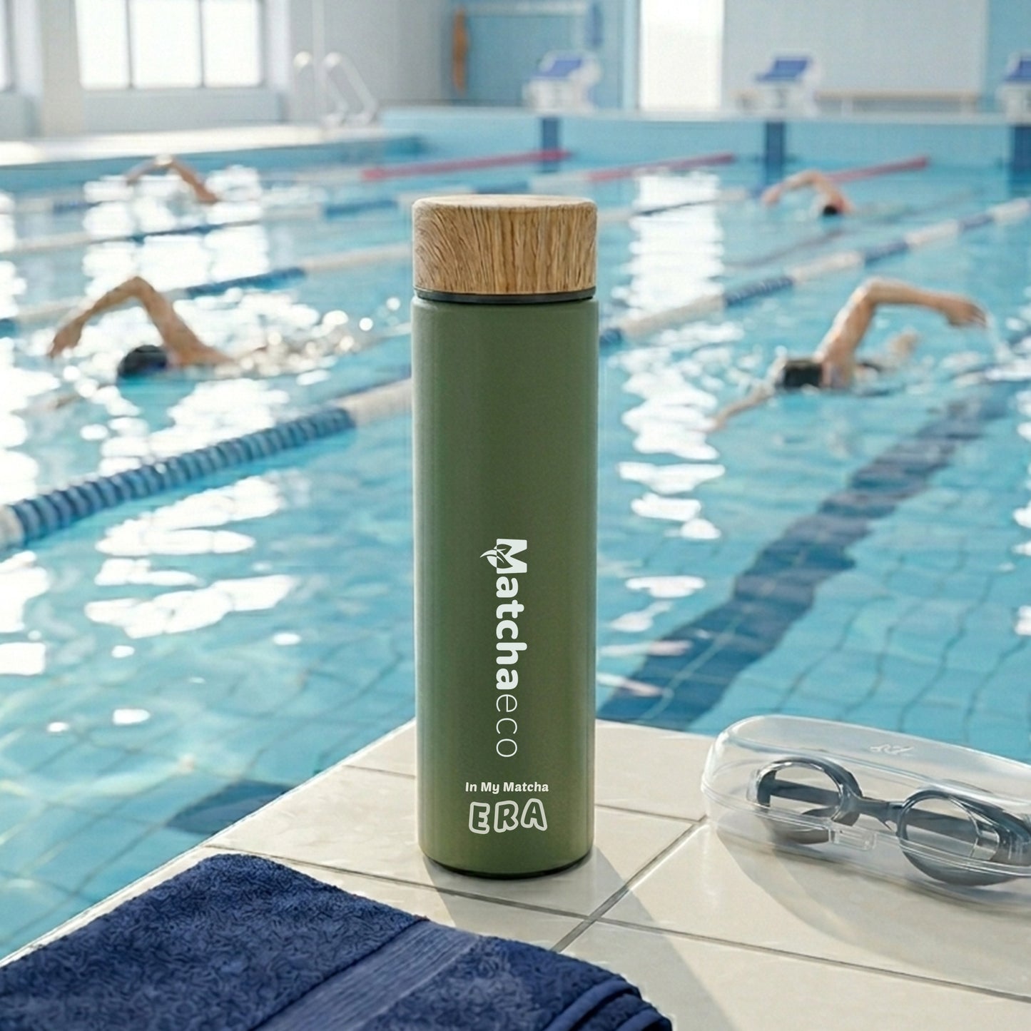 Green thermos bottle with cork lid on a pool deck with swimmers in the background