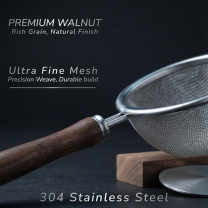 A close-up of a kitchen strainer with a dark brown walnut wood handle and a silver stainless steel mesh screen, resting on a wooden block against a dark background. Text overlays highlight the premium walnut finish, ultra fine mesh, and 304 stainless steel construction.
