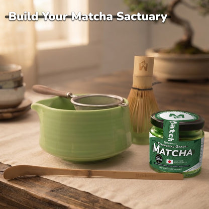 A styled matcha tea preparation setup on a wooden table with a light green ceramic bowl, metal strainer, bamboo whisk, bamboo scoop, and a jar of Matcha green tea. The text 'Build Your Matcha Sactuary' is overlaid at the top.